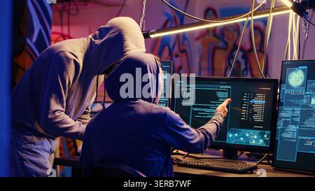 Evil cybercriminals in graffiti sprayed hideaway targeting vulnerable unpatched connections, discussing ways of getting past computer defenses and stealing valuable sensitive data. Stock Photo