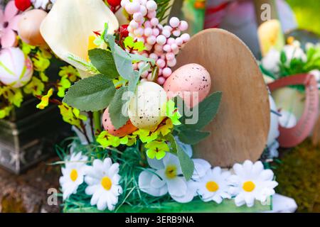 Easter flower arrangement with colorful speckled eggs daisy flowers and a blank wooden egg sign close up Stock Photo