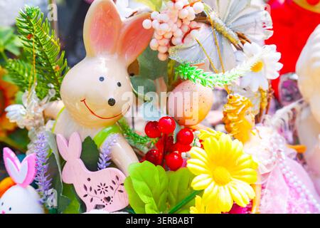 Easter flower arrangement with a cute ceramic bunny figurine colorful eggs and spring daisies close up Stock Photo