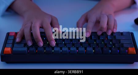 Hands typing on modern backlit keyboard for digital technology work and gaming coding close Stock Photo