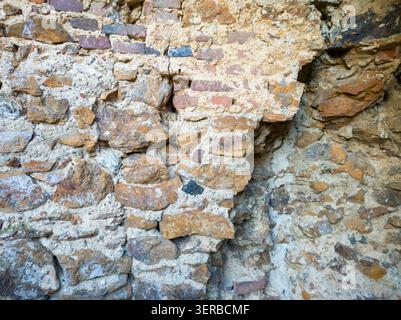 Full frame texture of an ancient weathered wall made of mixed stone bricks and mortar layers. Stock Photo
