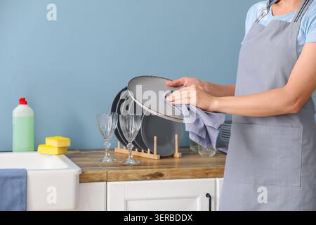 Woman in apron drying clean plate with cloth in kitchen, household chores and domestic life Stock Photo