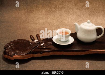 Chinese tea set with white teapot and teacup on a wooden tea tray. Stock Photo