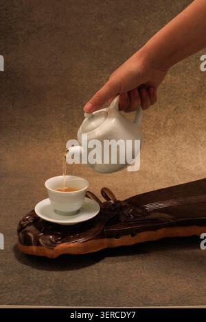 Chinese tea set with white teapot and teacup on a wooden tea tray. Stock Photo