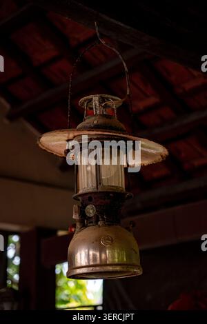 Antique rusty kerosene lantern hanging from wooden beam ceiling in traditional Vietnamese house Stock Photo
