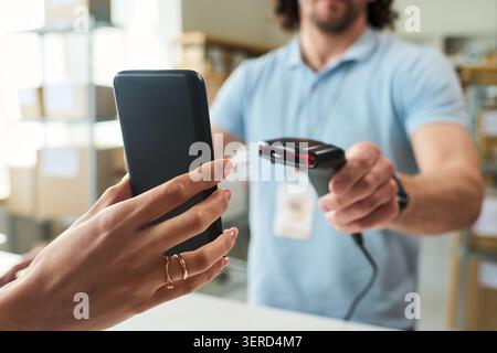 Woman Paying by Smartphone at Order Pickup Counter Stock Photo