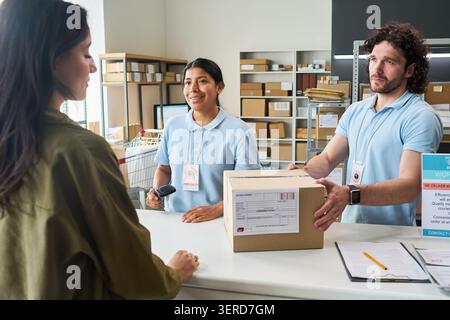 Diverse Delivery Workers Handling Customer Pickup at Parcel Counter Stock Photo