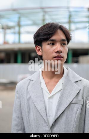 Authentic vertical close up portrait of a young non-binary Thai Isan developer or engineer looking away thoughtfully. Strategic vision concept standin Stock Photo
