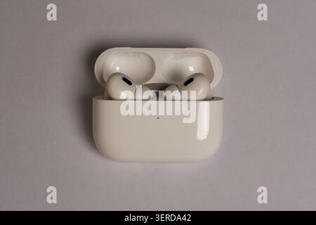 White earbuds rest in open charging case. Minimalist design with clean, smooth surfaces. Neutral background highlights product simplicity. Quiet, stil Stock Photo