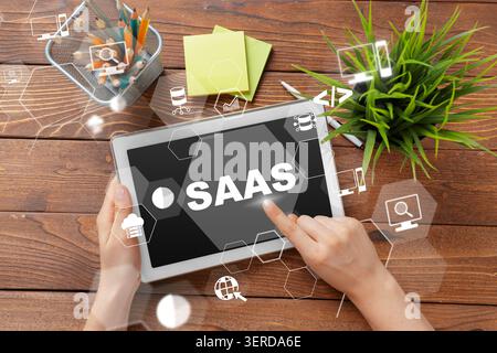 Saas software displayed on tablet with workspace items including plant and notepads Stock Photo