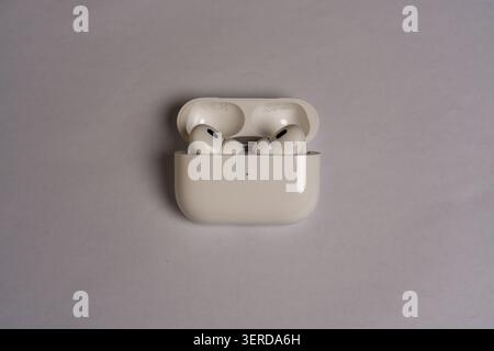 White earbuds rest in open charging case. Simple background highlights device design. Minimalist setup emphasizes product clarity. Smooth curves and c Stock Photo