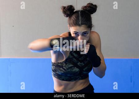 Determined female fighter practicing sharp punches during highenergy workout session inside gym Stock Photo