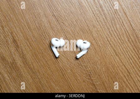 White earbuds rest on a wooden surface. Simple, clean design against warm wood grain. Minimalist setup ideal for tech or lifestyle visuals. Perfect fo Stock Photo