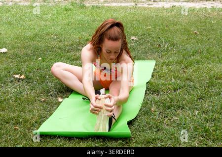 Active woman performing warmup. Young lady engaging in outdoor mobility exercise Stock Photo