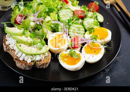 Healthy Keto Salad with Avocado and Soft Boiled Eggs on Dark Background Stock Photo