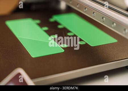 Green plastic parts printed on 3D printer build plate, additive manufacturing result Stock Photo