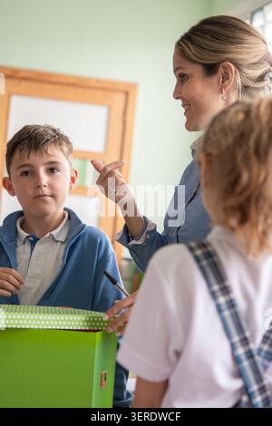 Primary school teacher interacting with students during a hands-on classroom activity. Stock Photo
