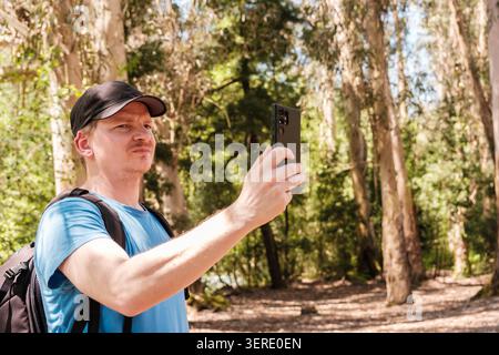 Man in forest using mobile phone for taking pictures or recording video Stock Photo