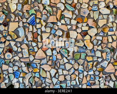Many broken pieces of antique pottery and ceramic fragments arranged as an intricate mosaic pattern, forming a unique background texture - stock photo Stock Photo