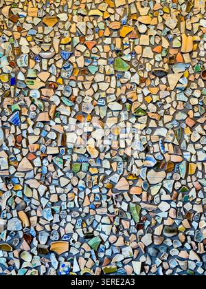 Recycled antique ceramic pottery shards creating a vibrant textured mosaic, showcasing a pattern of broken fragments embedded as a historical. Stock Photo