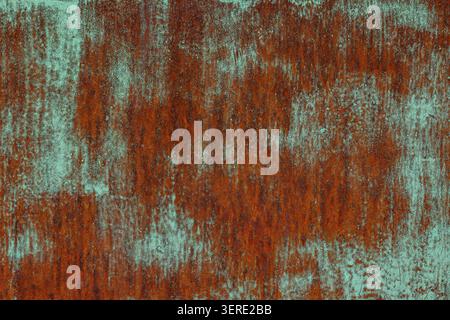Close-up texture of a flat weathered metal surface featuring a rusty texture with leftovers of turquoise paint. Stock Photo