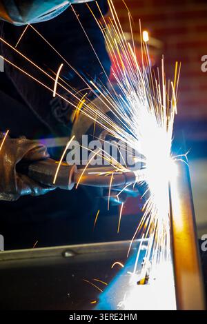 Close up of professional welder creating bright sparks during metal welding Stock Photo