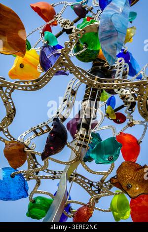 A detailed close-up shot of a vibrant kinetic sculpture, showcasing a complex metal framework adorned with numerous colorful glass elements. Many of t Stock Photo