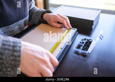 Man measuring a picture frame with a tape measure while working on home improvement Stock Photo