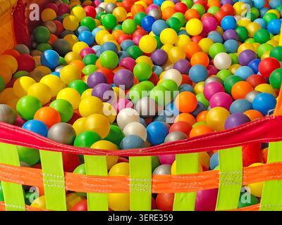 Colorful plastic balls filling a children's ball pit in an indoor playground. Bright multicolored spheres creating a vibrant full-frame background wit Stock Photo