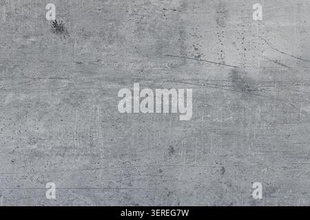 A grey concrete surface with visible textures and marks. The surface appears worn out and has several lines and spots. Stock Photo