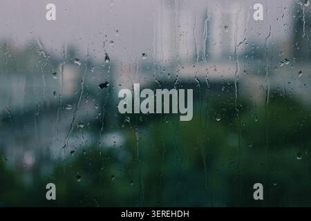 Drops of water on a window glass surface with condensation. Wet glass texture background. Water droplets on a window glass in rainy weather. Stock Photo