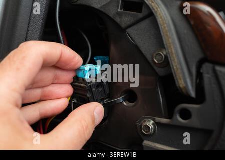Mechanic hand removing a car fuse from the vehicle fuse box. Close-up of replacing a burnt automotive electrical fuse. Stock Photo