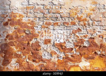 Close up of the façade of a brick wall with weathered yellow paint and plaster Stock Photo