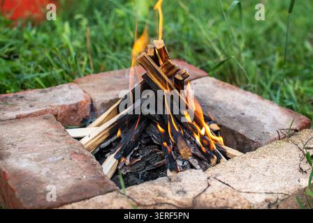 Bonfire flame in handmade brick fire pit outdoors Stock Photo