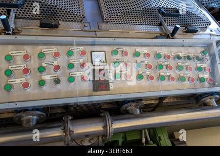 Close up of an electrical control panel with vintage switches, indicator lights, and digital temperature displays on a Greek olive oil extraction mach Stock Photo