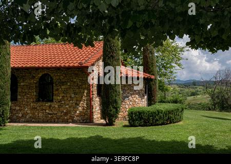 Stone chapel with red tiled roof in green countryside Stock Photo