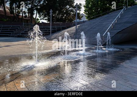 Water Jets in Urban Fountain on Wet Stone Pavement Stock Photo