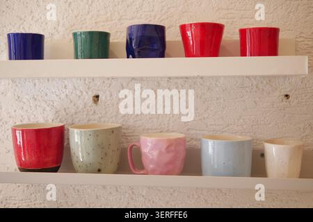 Colorful cups are displayed on a shelf in a cafe Stock Photo