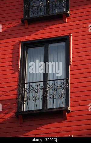 Window with black iron balcony on red wooden house Stock Photo