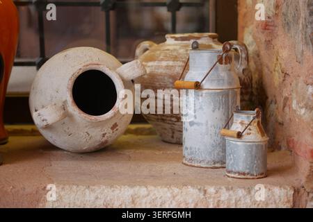 Old pottery and milk jugs on a stone shelf in a room Stock Photo