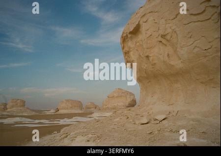 A close-up ground-level view of a massive eroded chalk rock formation in Egypt's White Desert (Sahara el Beyda), its wind-sculpted surface showing dra Stock Photo