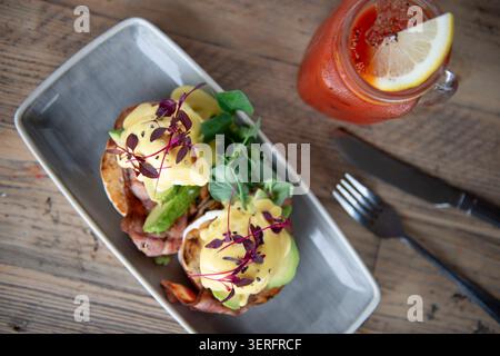 Delicious Brunch Delight With Eggs Benedict and Refreshing Drink Served on Rustic Table Stock Photo