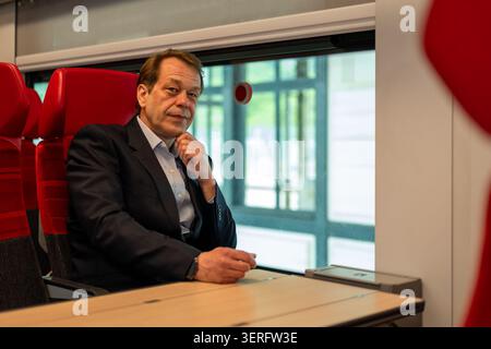 Middle aged businessman in a business suit sits in a train during travel Stock Photo