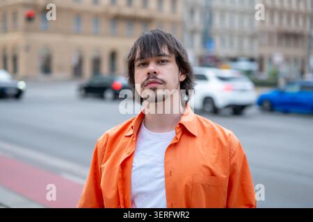 Young man stands on a city street against a background of traffic Stock Photo
