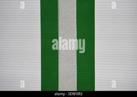 Abstract flag-like structure of green and grey tape on a white corrugated plastic surface Stock Photo
