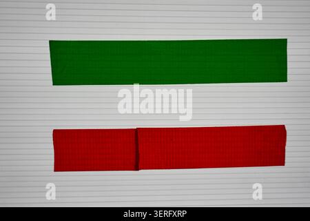 Minimalist background with green and red fabric textured tape stripes on white lined paper with copy space Stock Photo