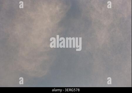 A muted blue sky filled with soft, diffuse white and gray clouds creating a calm, overcast atmosphere. Gentle tones evoke a peaceful, dreamy mood. Stock Photo