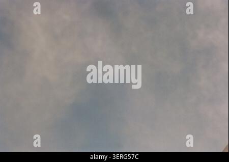 A muted, overcast sky filled with soft gray and white clouds, creating a calm and subdued atmospheric mood. Slight film grain texture adds a vintage q Stock Photo