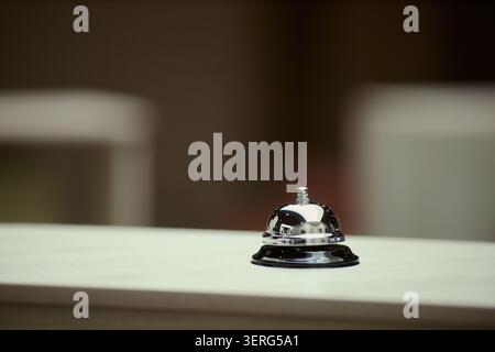 Close up of hotel reception bell standing on counter, representing hospitality service, guest check in, travel support. Ideal for tourism marketing, booking platforms, concierge ads Stock Photo