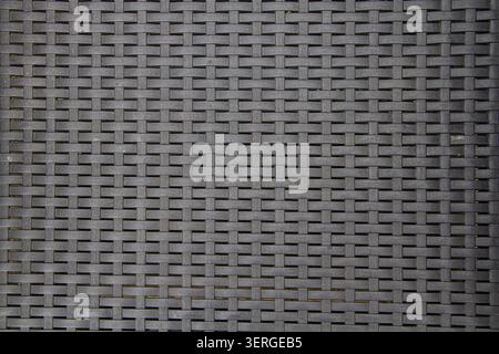 Background image of black plastic strips woven to look like a wicker panel with copy space Stock Photo